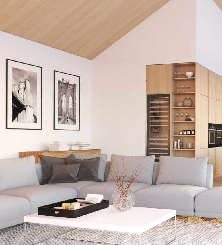 Modern living room with a gray sectional sofa, a white coffee table with a vase, and framed bridge photos on the wall. Open kitchen area with wood cabinets and a built-in wine cooler. Modern living room with a gray sectional sofa, a white coffee table with a vase, and framed bridge photos on the wall. Open kitchen area with wood cabinets and a built-in wine cooler.